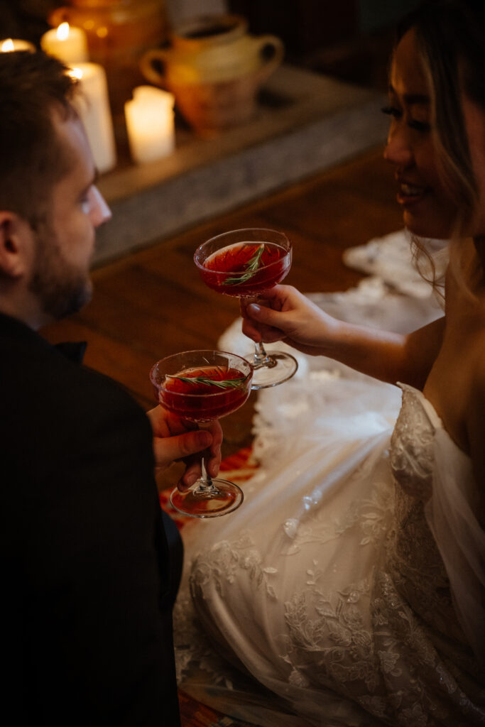 Couple drinking cocktails by the fire at Elcott Park for wedding