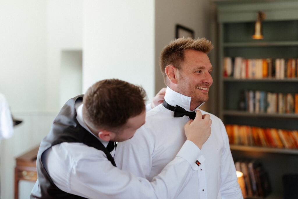 Groom prep in the library at Hyde House by Cotswolds wedding photographer