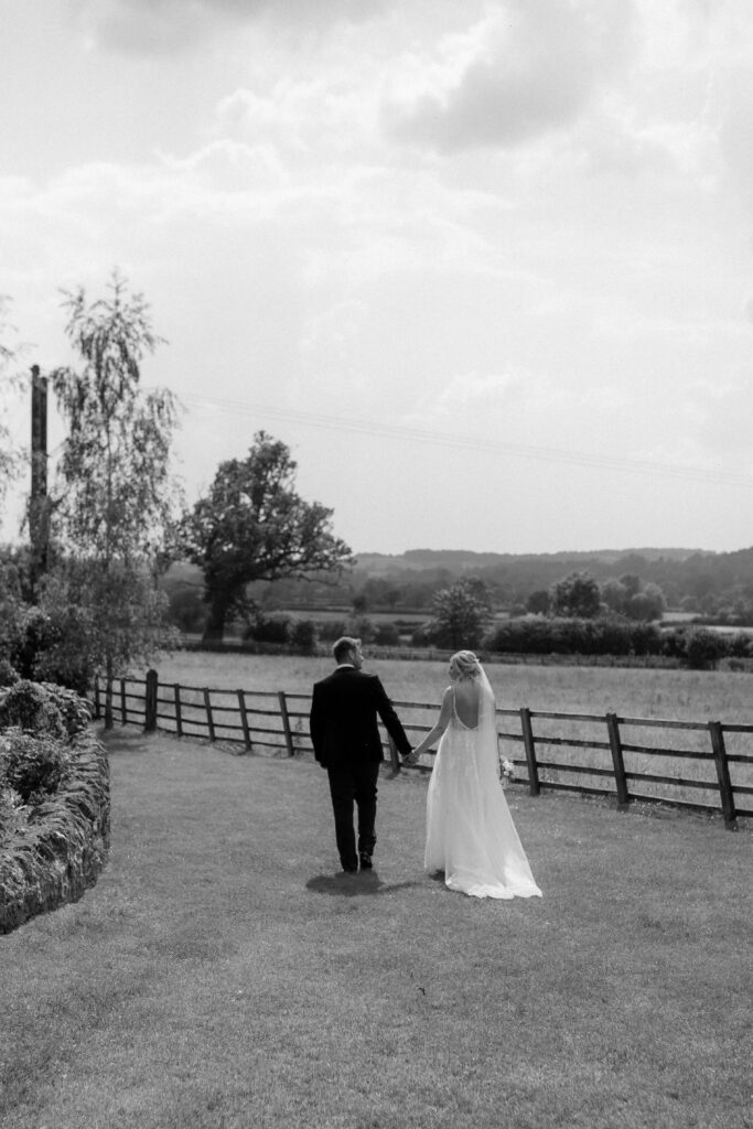 bride and groom walking in grounds of hyde house by cotswolds wedding photographer